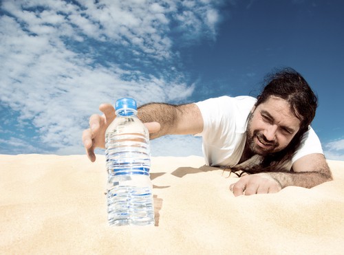 man in desert reaches for water