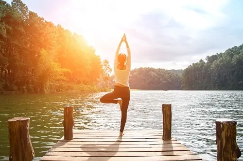 woman doing yoga on dock by lake